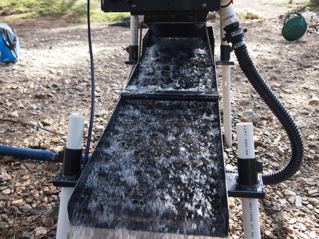 Water running over gold hog mats in sluice run